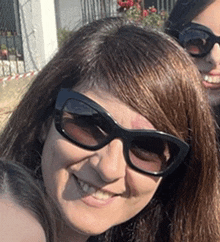 a woman wearing sunglasses smiles for the camera