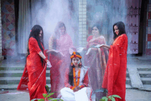 a woman in a white dress is surrounded by other women in red clothes