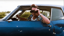 a man is sitting in a car looking through binoculars .