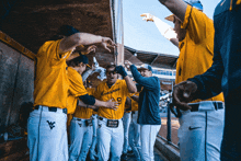 a group of baseball players are huddled together in a dugout and one of the players is wearing a virginia tech shirt