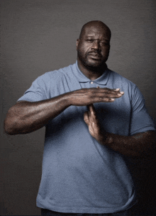 a man wearing a blue shirt is making a stop sign with his hands