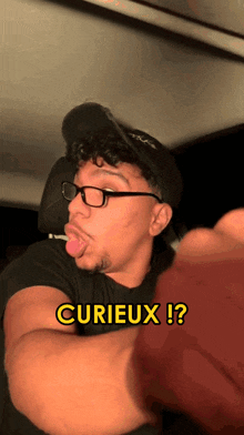 a man wearing glasses and a hat is making a funny face with the words cuieux ! written below him