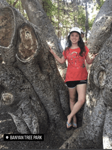 a girl in a red shirt is standing next to a tree with banyan tree park written on the bottom