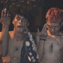 a shirtless man with a spider tattoo on his chest is giving the middle finger to another shirtless man