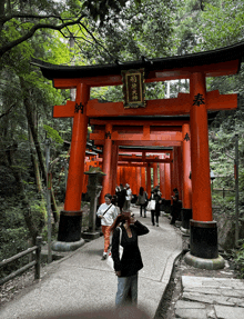 a group of people standing in front of a torii gate with chinese writing on it