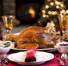 a turkey is sitting on a plate on a table with a christmas tree in the background