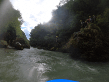 a group of people in yellow helmets are standing on a rock near a river