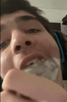 a close up of a person 's face with a white object in his mouth