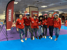 a group of people posing for a photo in front of a banner that says savana