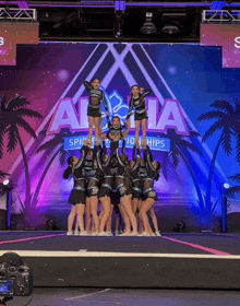 a group of cheerleaders perform on a stage in front of a sign that says aloha spirit championships