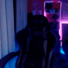 a black gaming chair is sitting in front of a window in a room .