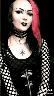 a woman with pink and black hair is wearing a choker and a necklace