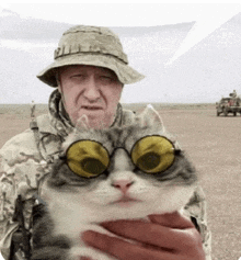 a man in a military uniform is holding a cat with yellow glasses on .