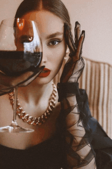 a woman holding a glass of wine with her hand over her face