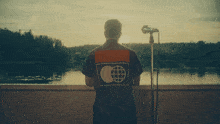 a man stands in front of a microphone looking out over a body of water