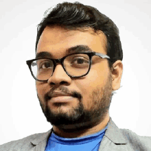 a man wearing glasses and a blue shirt is looking at the camera