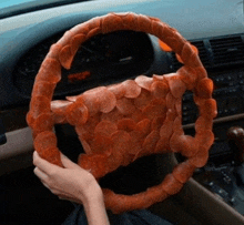 a person is holding a steering wheel made of pepperoni chips