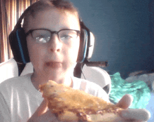 a young boy wearing headphones and glasses is eating a sandwich