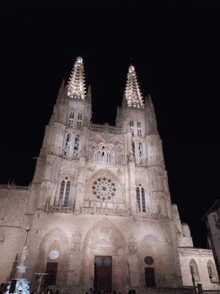 a large building is lit up at night with a clock on the front