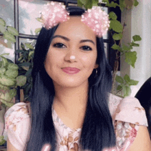 a woman with long black hair wearing a pink flower crown