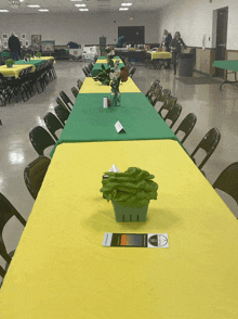 a long table with a yellow table cloth and a green table cloth has a sign on it that says ' a ' on it