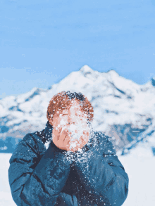 a person blowing snow in front of a mountain