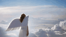 a woman in a white dress with angel wings stands in the clouds