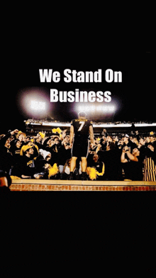 a football player stands in front of a crowd with the words " we stand on business " above him