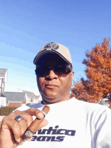 a man wearing a nautica jeans shirt holds a cigar in his hand