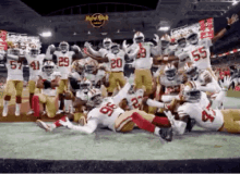 a group of football players are posing for a picture on a field in front of a hard rock cafe .