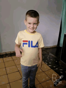 a young boy wearing a yellow fila shirt smiles for the camera