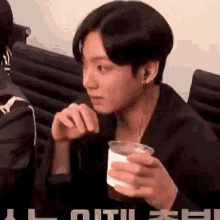 a man is sitting in a chair holding a glass of milk .