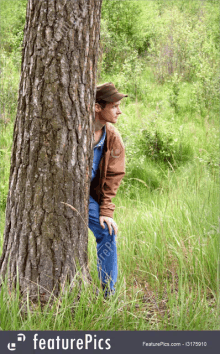 a man leaning against a tree in a forest