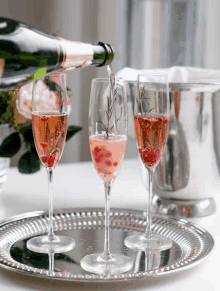 a bottle of champagne is being poured into three champagne glasses