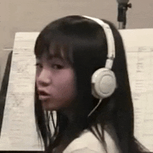 a woman wearing headphones is sitting in front of a microphone in a recording studio .