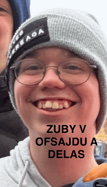 a man wearing glasses and a beanie with the words zuby v ofsajdu a delas written on it