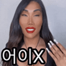 a woman with long hair and red lips is smiling and holding her hand up with the word choix on it .