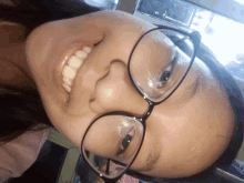 a young girl wearing glasses is smiling and looking at the camera