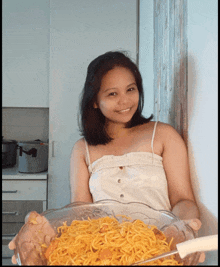 a woman holding a bowl of noodles with a fork