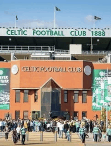 a group of people are gathered in front of the celtic football club