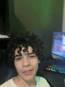 a young man with curly hair is sitting in front of a laptop