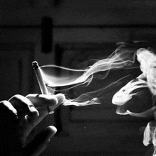 it is a black and white photo of a person smoking a cigarette .