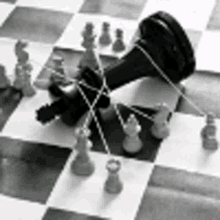 a black and white photo of a chess board with pieces tied together with string .