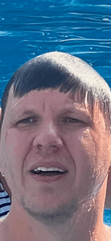 a man with water on his face is smiling in front of a blue pool