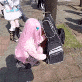 a person in a pink wig is kneeling next to a guitar case that says ' fender ' on it