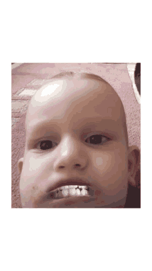 a close up of a baby 's face shows his teeth