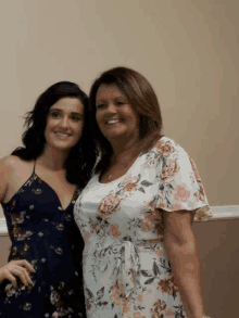 a woman in a floral dress is standing next to another woman