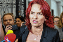 a woman with red hair stands in front of a microphone that says toke