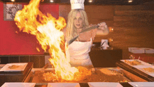 a woman in a chef 's hat is cooking food with flames coming out of the pan