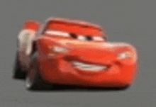 a red car from the movie cars is smiling and driving on a road .